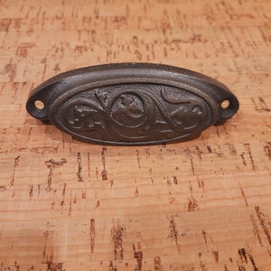 May include: A black cast iron drawer pull with an ornate floral design.