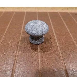 May include: A small, gray ceramic mushroom-shaped knob with a speckled finish.