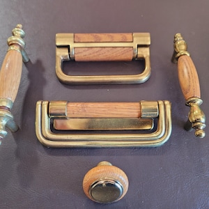 May include: Set of five brass and wood cabinet hardware pulls. The pulls feature a wood center with brass accents. The set includes two long pulls, two short pulls, and one knob.