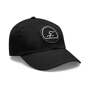 May include: Black baseball cap with a curved brim and a white circular patch. The patch features a minimalist design in white, stitched onto the cap. The cap is made of a durable fabric and has a button on top.