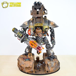 May include: A detailed model of a large, mechanical war machine with a weathered, metallic finish. The model features intricate details, including a large weapon, a cockpit, and a base with miniature figures. The color palette includes shades of gray, brown, and orange.