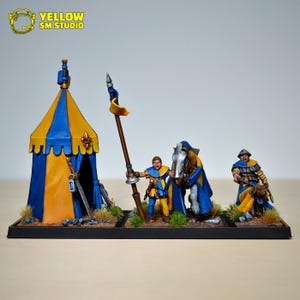 May include: Miniature medieval scene featuring a yellow and blue striped tent, a soldier holding a spear, a horse, and another soldier with a dog. The figures are painted with detail, set on a black base. The text "YELLOW SM STUDIO" is in the upper left corner.