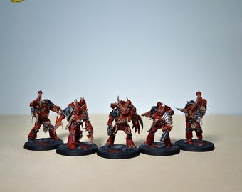 Peut inclure: Cinq figurines miniatures de guerriers en armure rouge et argent, posées sur des socles circulaires noirs. Les figurines ont des armures et des armes détaillées. Le texte "YELLOW SM STUDIO" est dans le coin supérieur gauche.