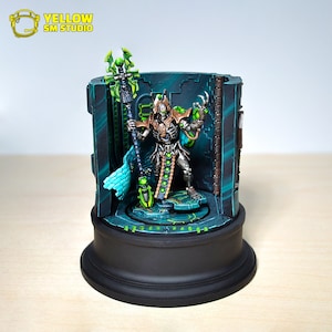 May include: A detailed miniature figure of a skeletal figure in a green and brown robe holding a staff with green glowing orbs. The figure is standing on a circular platform with a green and black background.