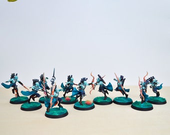 Peut inclure: Un groupe de dix figurines miniatures d'elfes peintes en bleu et rose avec des arcs et des flèches. Les figurines sont posées dans une variété de poses dynamiques, suggérant l'action et le mouvement. Les figurines sont sur un fond blanc.