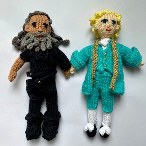 Peut inclure: Deux poupées en tricot, l'une avec une tenue noire et une longue barbe grise, l'autre avec une tenue turquoise et des cheveux blonds.