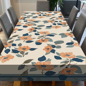 May include: A white tablecloth with a floral pattern featuring orange flowers and blue leaves. The tablecloth is laid on a wooden table with gray chairs.