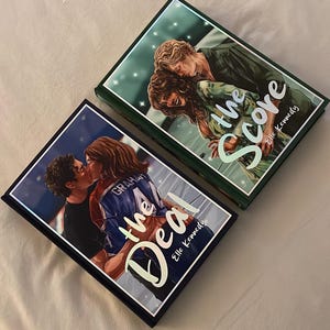Op de afbeelding: Twee gebonden boeken met geïllustreerde covers. Het eerste boek, getiteld The Deal van Elle Kennedy, toont een kussend stel. Het tweede boek, getiteld The Score van Elle Kennedy, toont een geïllustreerd stel in een groen getinte omgeving.