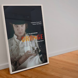 以下が含まれることがあります： スタンリー・キューブリック監督の映画「時計じかけのオレンジ」の映画ポスター。ポスターには、ボウラーハットと白いシャツを着た主人公アレックスのクローズアップが写っている。「時計じかけのオレンジ」という文字は赤とオレンジの文字で、「イニシアチブはそれを求める人々にやってくる」という引用は白い文字で書かれている。