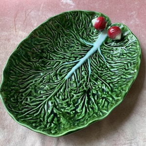 Op de afbeelding: Een groene keramische serveerschaal in de vorm van een koolblad met twee rode radijsaccenten.