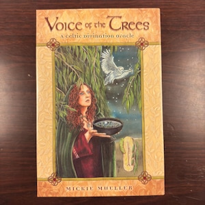 Puede incluir: Un libro titulado "Voice of the Trees: A celtic divination oracle" de Mickie Mueller. La portada presenta a una mujer con una capa verde sosteniendo un cuenco, un búho blanco volando en el fondo y un sauce llorón.