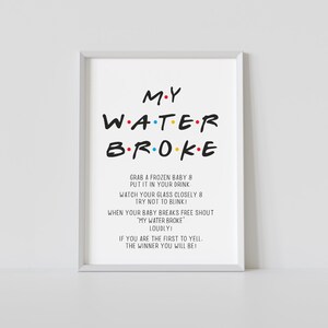 May include: A framed print with the text "MY WATER BROKE" in a colorful, stylized font. Below, instructions for a baby shower game are printed in black text. The frame is white, and the background is white.