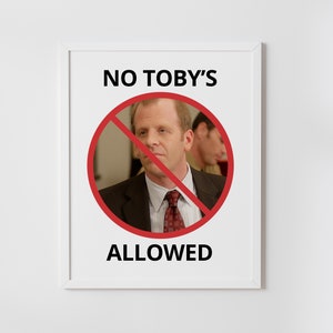 May include: A white framed sign with the text "NO TOBY'S ALLOWED" in black letters. A red circle with a diagonal red line through it surrounds a photo of a man in a suit and tie.