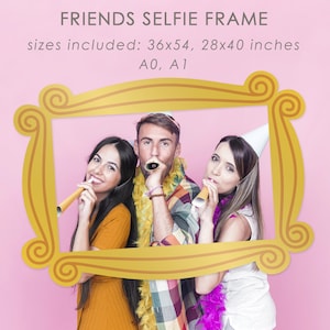 Puede incluir: Tres amigos posan para una foto en un marco de selfie de estilo Friends de la serie de televisión, de color dorado. El marco está sobre un fondo rosa. El marco está disponible en los tamaños 36x54, 28x40 pulgadas, A0 y A1.