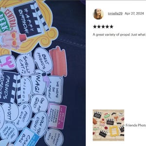 May include: A collection of paper photo booth props featuring various shapes and phrases inspired by the television show Friends. The set includes speech bubbles, clapperboards, a yellow picture frame, and icons like a lobster and a couch.
