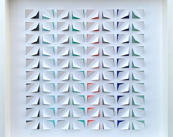 Könnte beinhalten: Ein weiß gerahmtes Kunstwerk mit einem geometrischen Muster aus weißen, grauen, blauen, grünen und roten Papierquadraten.