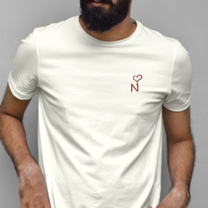 Peut inclure: T-shirt blanc avec un cœur rouge et la lettre N sur le devant.