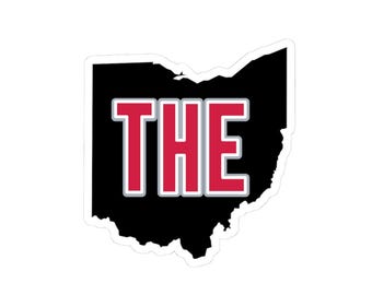 May include: A sticker featuring the outline of Ohio in black, with the word "THE" in red letters with a white border. The sticker is die-cut and has a white background.