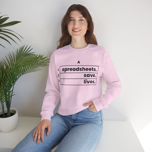 May include: A pink sweatshirt with a black graphic that says "spreadsheets. save. lives." in a table format.