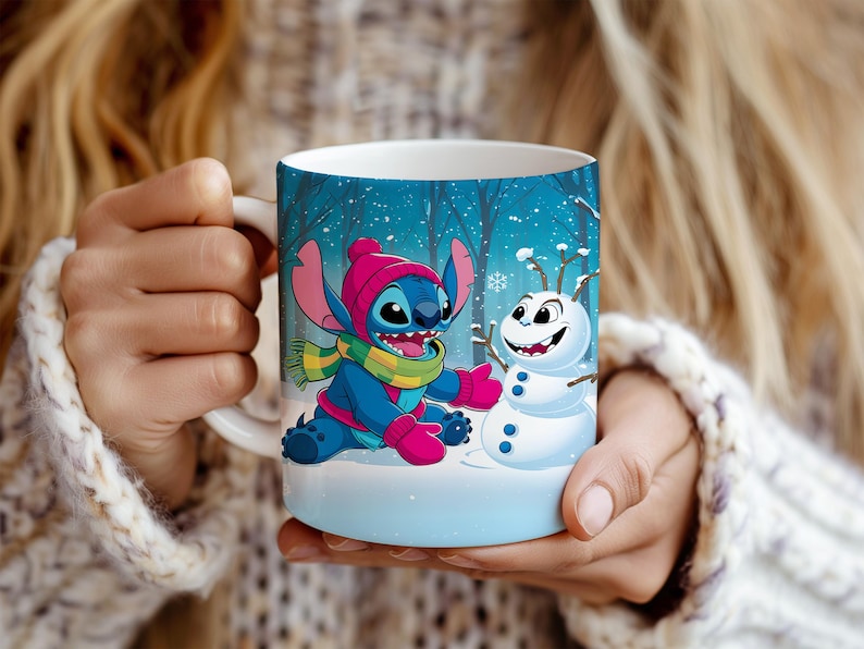 May include: A white ceramic mug featuring Stitch from Lilo & Stitch, wearing a pink hat, scarf, and gloves, and Olaf the snowman. The mug has a winter forest scene background with falling snow. The mug is held by a person.