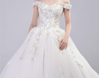 Vestido de novia con escote estilo vasco, hombros descubiertos, escote en V, perlas adornadas con abundante encaje, vestidos de novia con cola catedral en color marfil.