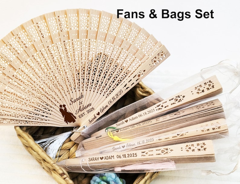 Op de afbeelding: Een set houten waaiers met een gepersonaliseerd bericht voor een bruiloft. De waaiers zijn versierd met een dansend stel en de tekst "Sarah & Adam EST. 2025". De waaiers zijn verpakt in een doorzichtige plastic zak met een wit lint.