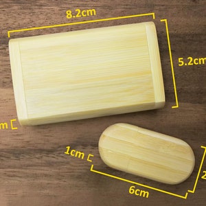Op de afbeelding: Twee houten dozen gemaakt van bamboe. De grotere doos is 8,2 cm lang, 5,2 cm breed en 1,9 cm hoog. De kleinere doos is 6 cm lang, 2,8 cm breed en 1 cm hoog.