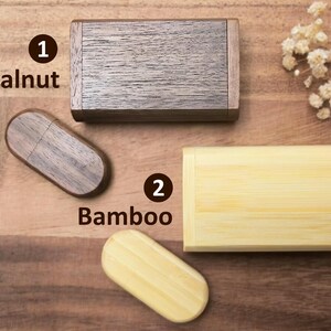 Op de afbeelding: Twee houten USB-sticks, een van walnoot en een van bamboe. De walnoot-stick is rechthoekig gevormd en de bamboe-stick is rechthoekig gevormd. De sticks liggen op een houten oppervlak.