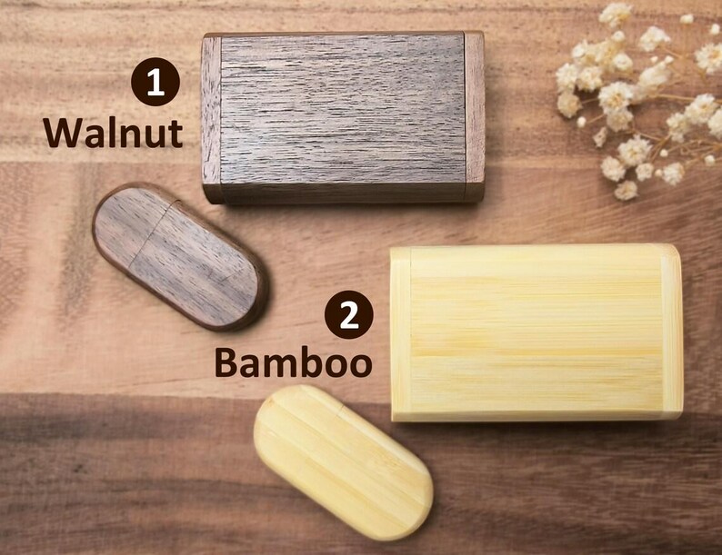 Op de afbeelding: Twee houten USB-sticks, een van walnoot en een van bamboe. De walnoot-stick is rechthoekig gevormd en de bamboe-stick is rechthoekig gevormd. De sticks liggen op een houten oppervlak.