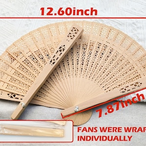 May include: Two open wooden fans with intricate cut-out designs. Each fan measures 12.60 inches wide and 7.87 inches high. A smaller, wrapped fan is visible. The fans are light brown and appear to be made of wood.