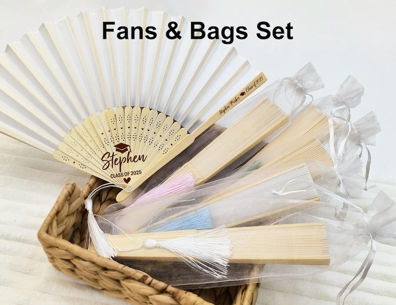 May include: A set of white hand fans with personalized wooden handles and white organza bags. The fans have a white paper surface and a wooden handle with the text "Stephen Class of 2025" printed on it. The bags are made of sheer white organza fabric and have a drawstring closure.