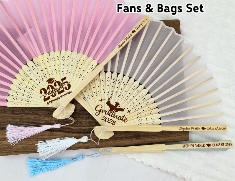 May include: Two personalized hand fans with tassels. The fans are made of bamboo and have a white silk fabric. One fan has the text "Graduate 2025" and the other has the text "Class of 2025 Stephen Parker".