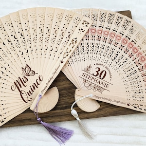 Op de afbeelding: Twee houten handventilatoren met ingewikkelde uitsnijdingen en gepersonaliseerde berichten. De eerste ventilator zegt "Mis Quince" en "Happy birthday, Stephanie!" De tweede ventilator zegt "Happy Birthday" en "30 Stephanie".