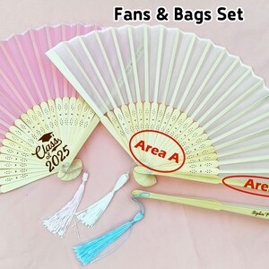 May include: Two hand fans with wooden handles and fabric covers. The pink fan has a graduation design with the text "Class of 2025". The white fan has the text "Area A" and "Area B" on the handle. The handle also has the text "Stephen Parker Class of 2025".