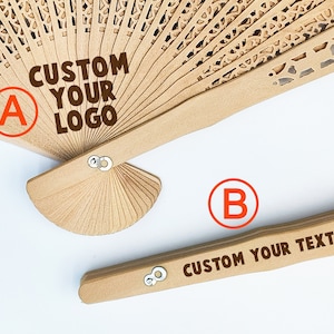 May include: Two wooden folding fans with custom text. The top fan has a brown handle and a white, intricate design. The text on the fan reads "CUSTOM YOUR LOGO". The bottom fan has a brown handle and a simple design. The text on the fan reads "CUSTOM YOUR TEXT".