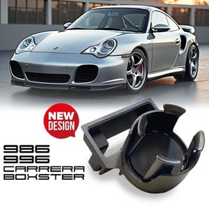 May include: Silver sports car with a black interior cup holder. The cup holder is black and has a "New Design" sticker. The text on the image reads "986 996 Carrera Boxster".