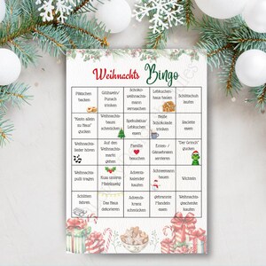 Puede incluir: Una tarjeta de juego de Bingo con tem&aacute;tica navide&ntilde;a, con palabras y frases en alem&aacute;n. La tarjeta presenta una cuadr&iacute;cula de actividades relacionadas con las fiestas, como "hornear galletas" y "decorar la casa". El dise&ntilde;o incorpora adornos y regalos navide&ntilde;os.