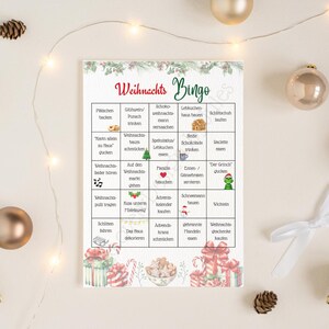 Puede incluir: Una tarjeta de juego de Bingo con tem&aacute;tica navide&ntilde;a, con palabras y frases en alem&aacute;n. La tarjeta presenta una cuadr&iacute;cula de actividades y frases relacionadas con las fiestas, con elementos decorativos como regalos y vegetaci&oacute;n. La palabra "Bingo" destaca.