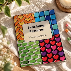 以下が含まれることがあります： 「Satisfying Patterns」というタイトルの塗り絵。表紙は4つの区画に分かれており、オレンジ色のシェブロン柄、青い正方形のタイル、緑色の水平な楕円形、黒い背景に赤いハートと紫色のハートが描かれ、中央にクリーム色のラベルが配置されています。