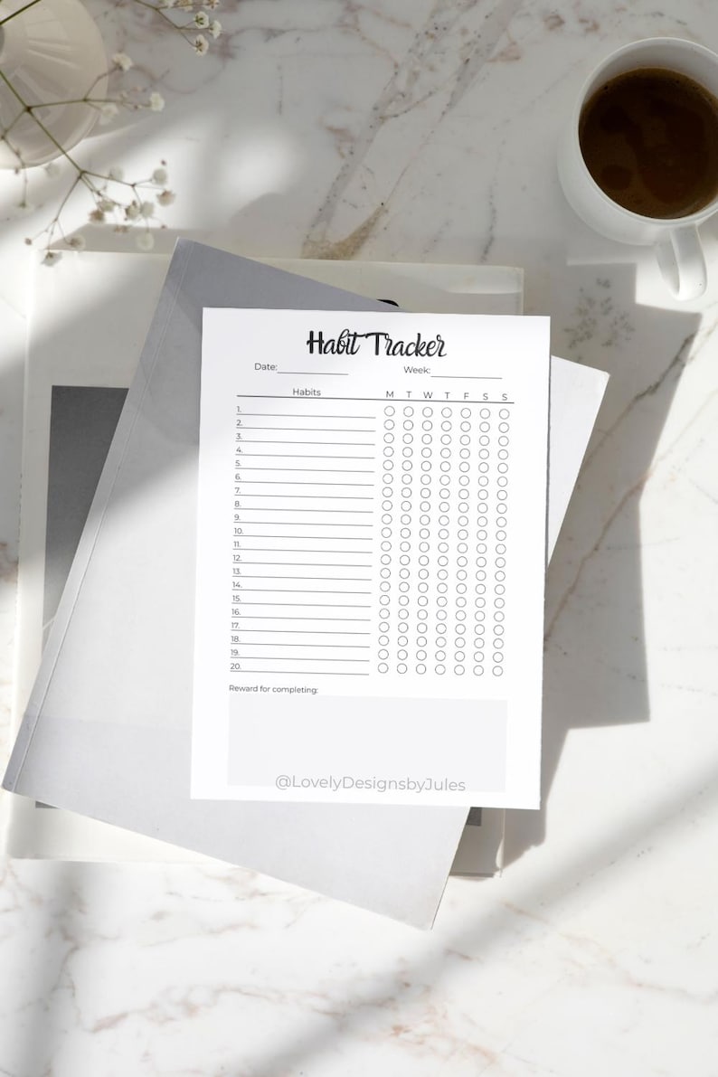 K&ouml;nnte beinhalten: Ein wei&szlig;es Habit-Tracker-Blatt mit dem Titel "Habit Tracker" in handschriftlicher Schrift. Das Blatt hat Platz f&uuml;r Daten, Gewohnheiten und Kontrollk&auml;stchen f&uuml;r jeden Wochentag. Eine Tasse Kaffee steht in der N&auml;he.