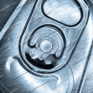 Può includere: Primo piano di una lattina d'argento con un anello di apertura. L'anello è parzialmente aperto, rivelando l'interno della lattina.