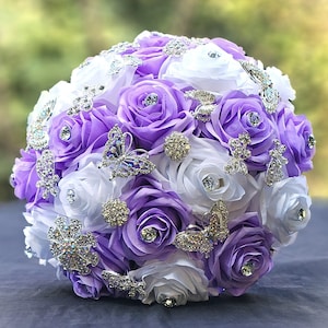 Lavande Quinceañera Ramos, bouquet, Lavande et fleurs blanches ornées de fleurs en argent et de broches papillon.