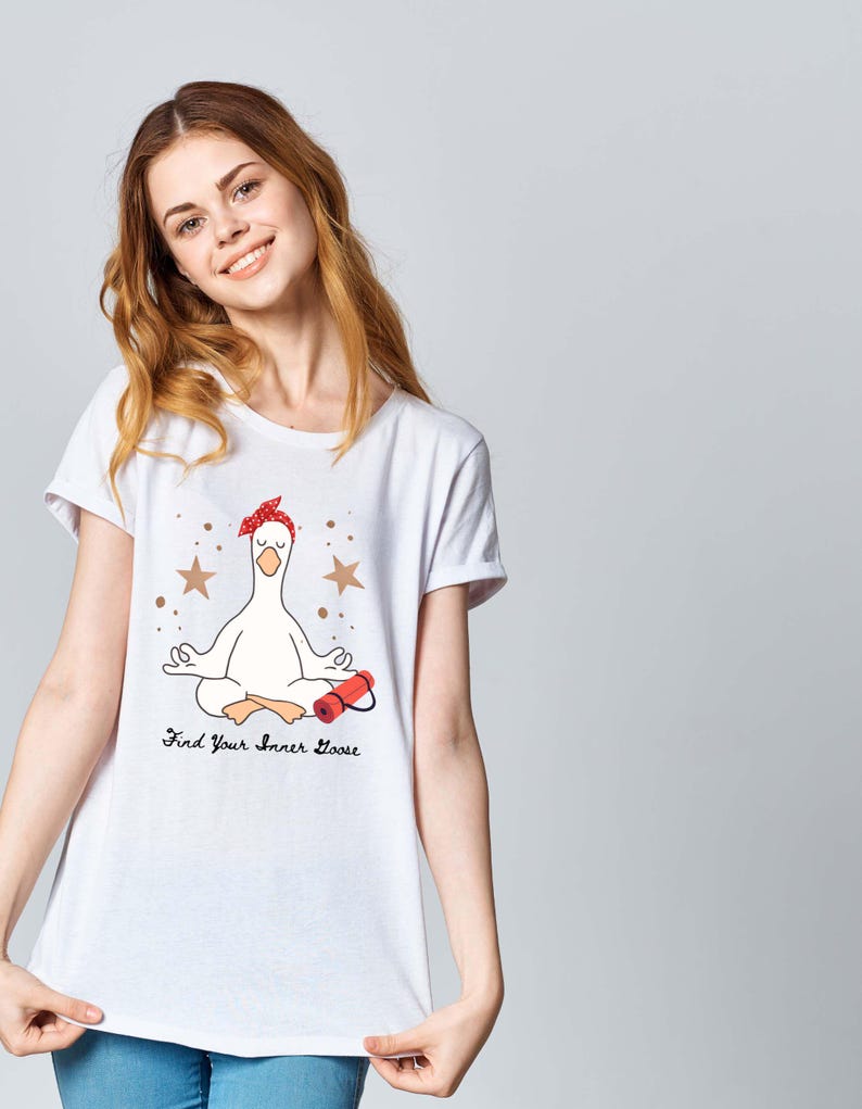 May include: White t-shirt with a cartoon goose in a yoga pose, wearing a red bandana and holding a red object. The shirt has the text "Find Your Inner Goose" with star accents.