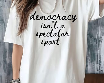 La democrazia non è uno sport da spettatori. Maglietta con citazione politica, 100% cotone.