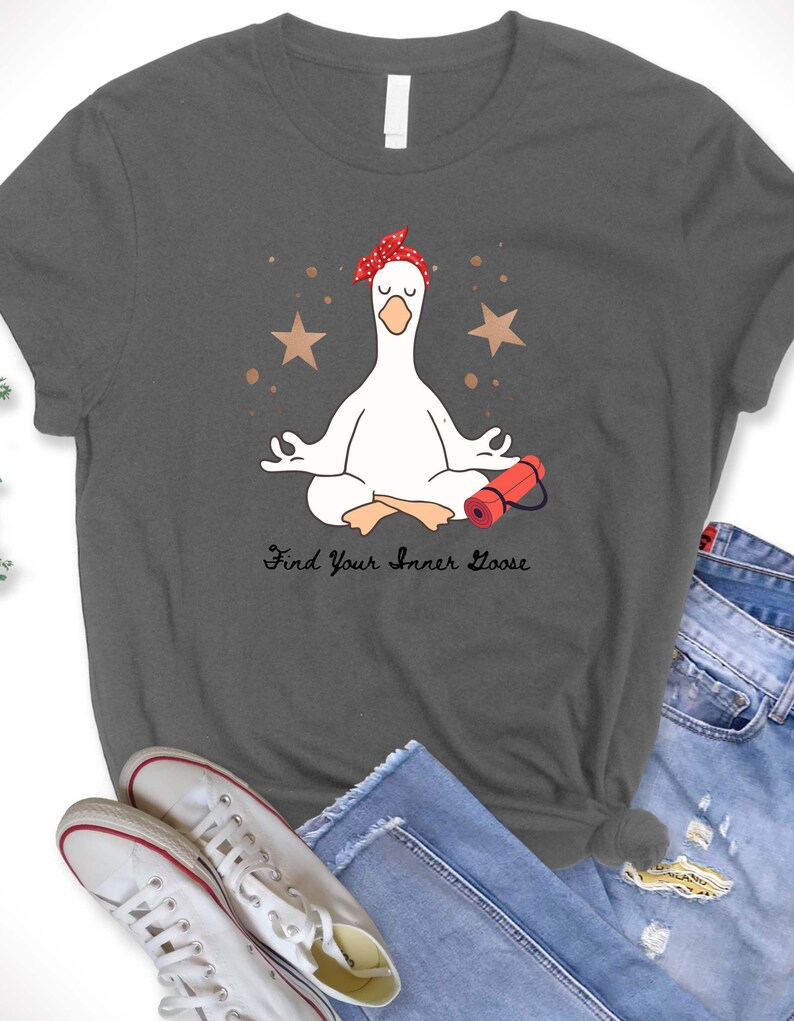 May include: Dark grey t-shirt with a cartoon goose in a yoga pose, wearing a red bandana. The design includes two brown stars and the text "Find Your Inner Goose". A red yoga mat is next to the goose.