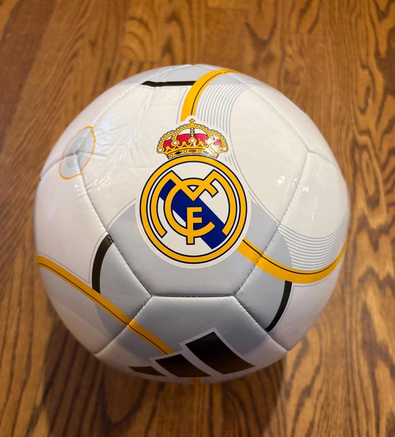 Puede incluir: Un juego de tres tazas de cer&aacute;mica con un esmalte moteado de color crema. Cada taza presenta un dise&ntilde;o pintado a mano diferente: una hoja azul y verde, una flor amarilla y una baya roja. Las tazas tienen una forma simple y redondeada.