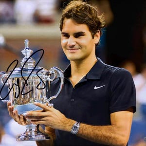 Puede incluir: Fotografía de un hombre sosteniendo un trofeo plateado con una firma. El hombre lleva un polo negro con el logo de Nike y un reloj. El trofeo es muy detallado y reflectante.