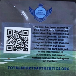 Puede incluir: Una tarjeta transparente con un c&oacute;digo QR y texto de Total Sports Authentics. El texto explica la autenticidad del art&iacute;culo, verificada por un holograma. El logotipo muestra un escudo con alas. La direcci&oacute;n del sitio web tambi&eacute;n es visible.