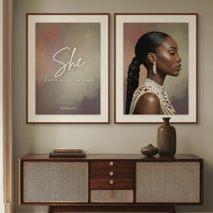 May include: Two framed art prints with brown wooden frames. One print features the word "She" in cursive with text below. The second print shows a woman wearing pearls. A wooden cabinet with woven panels and drawers is below.