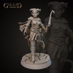Puede incluir: Una figura miniatura pintada en gris de un personaje femenino con cuernos, que lleva una capa, armadura y sostiene una hoja curva. La figura está de pie sobre una base circular con un diseño de piedra agrietada.